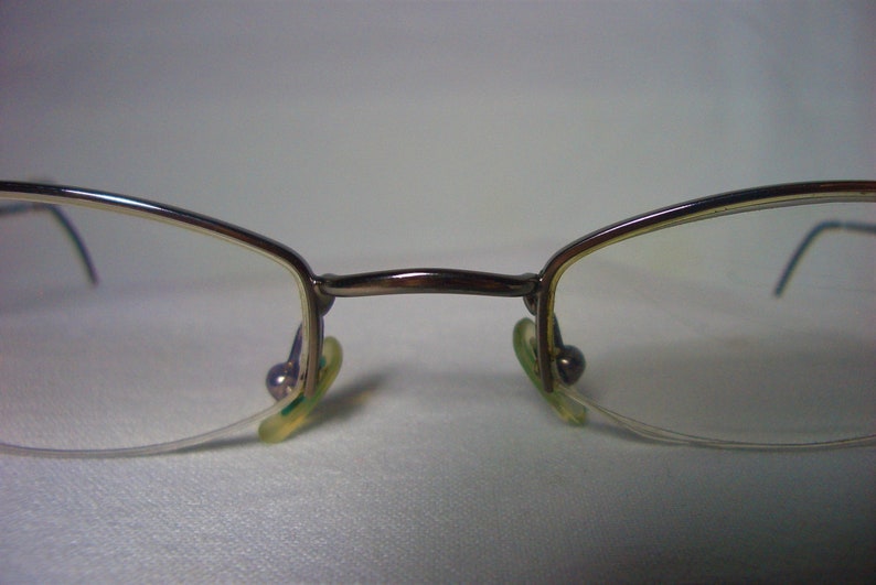 May include: A pair of silver-toned eyeglasses with clear lenses and green plastic earpieces.