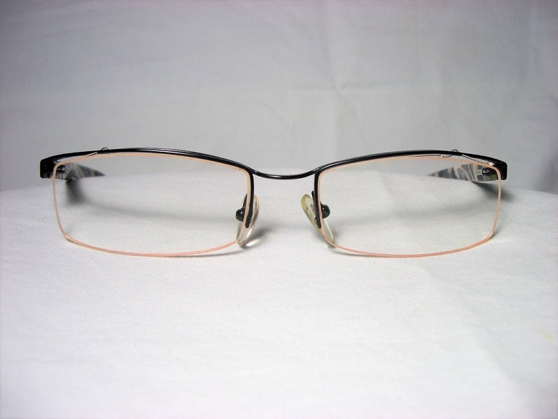 May include: Black rimless eyeglasses with a thin metal frame and clear lenses.