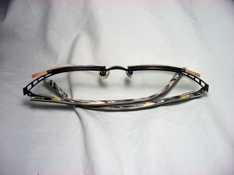 May include: Black and gold-toned eyeglasses with a tortoiseshell pattern on the arms. The glasses are folded in half.