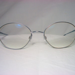 May include: Silver-toned oval-shaped eyeglasses with clear lenses.