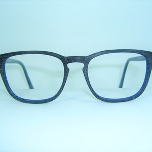 Puede incluir: Gafas negras con borde azul y un patrón de veta de madera en el marco.