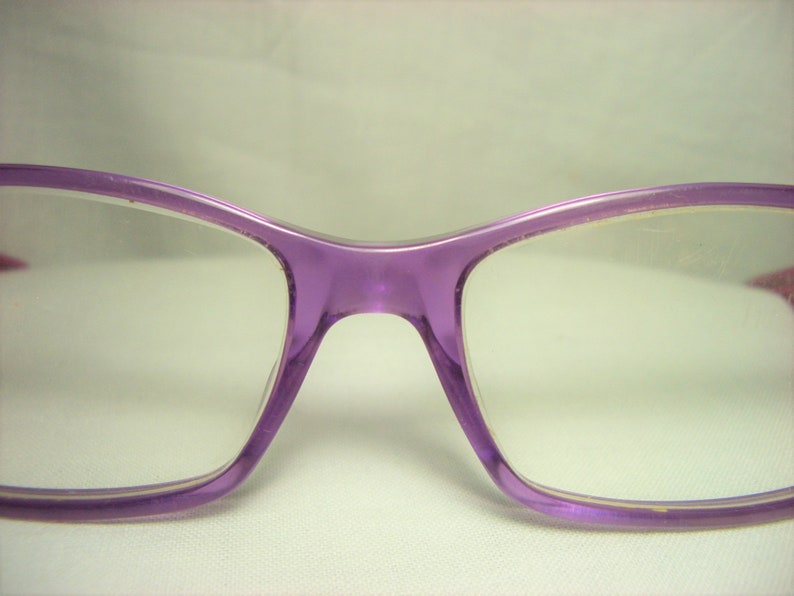 Puede incluir: Gafas de pl&aacute;stico de color morado con lentes transparentes.