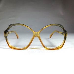 May include: A pair of brown and black plastic eyeglasses with a unique, geometric frame shape.