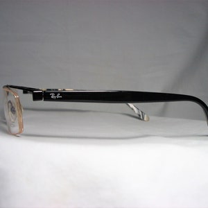 May include: Black rectangular eyeglasses with a brown frame and Ray-Ban logo on the side.