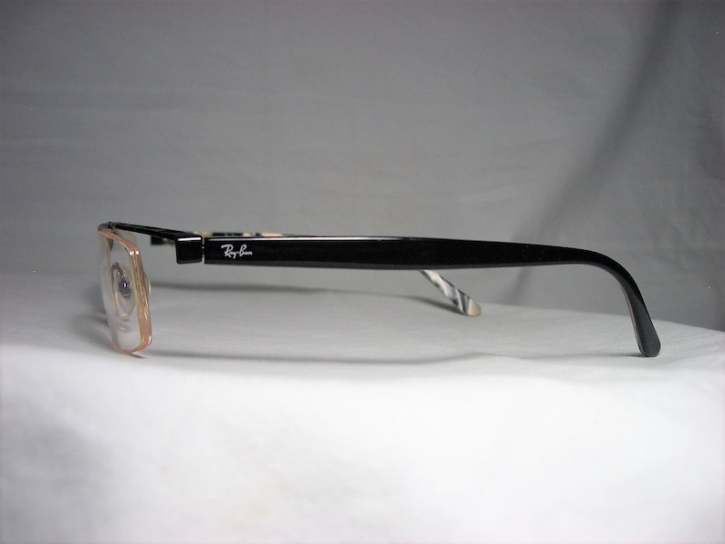May include: Black rectangular eyeglasses with a brown frame and Ray-Ban logo on the side.