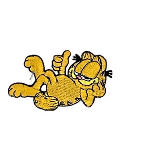 May include: Embroidered patch featuring Garfield the cat in a relaxed pose, giving a thumbs up. The patch is primarily orange with black accents and a pink tongue. The patch is designed for application on clothing or accessories.