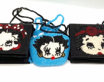 May include: Three beaded purses with a cartoon character design. The purses are black, blue, and black with red accents. Each purse has a beaded chain strap.