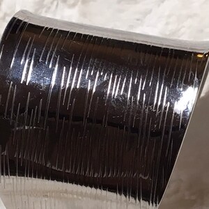 May include: A silver metal cuff bracelet with a textured, ridged design.
