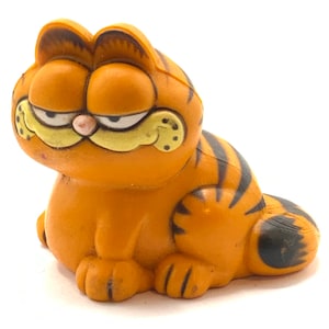 Vintage Garfield is  sitting, cat, orange, figurine.
