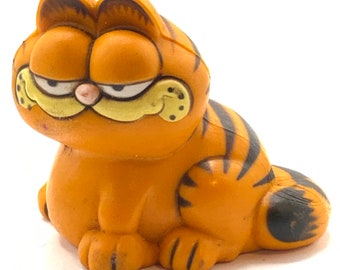 Vintage Garfield is  sitting, cat, orange, figurine.
