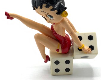 Gorgeous collectible and vintage Betty Boop ornament is sitting on dice.