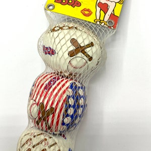 May include: Three white baseballs with red, white, and blue designs. The baseballs are in a clear plastic bag with a yellow tag that says "Betty Boop" with a cartoon image of Betty Boop.