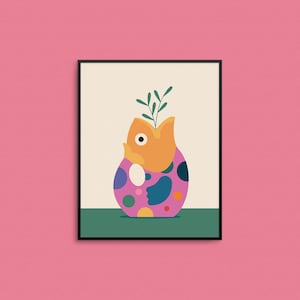 May include: A colorful, abstract vase with a fish-shaped opening and a green plant inside. The vase is sitting on a green surface and is framed in black.