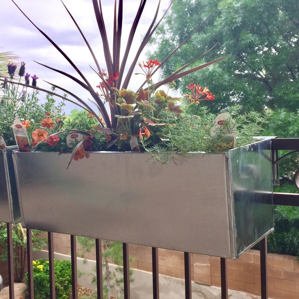 Metal planter boxes that set on patio railing.