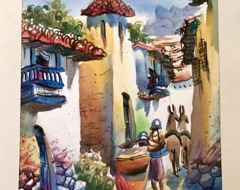 Op de afbeelding: Waterverf schilderij van een smalle straat in een dorp met witte gebouwen, rode pannendaken en blauwe balkons. Twee figuren lopen door de straat, een draagt een grote pot. Twee ezels zijn op de achtergrond.