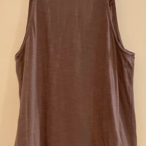 May include: A mauve sleeveless tank top with a black trim around the neckline.