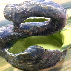 May include: A blue and green ceramic swan planter with a textured surface. The planter has two sections, one for planting and one for displaying.