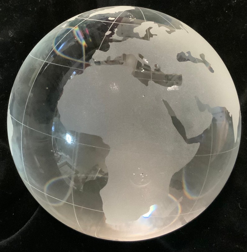 Op de afbeelding: Een matglazen globe met een gedetailleerde gegraveerde wereldkaart. De globe is helder en heeft een licht regenboogeffect door het licht dat van het oppervlak reflecteert.