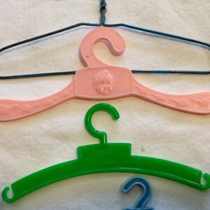 May include: Three plastic hangers, one pink with a child's face, one green with the word "remarkable" and one blue.