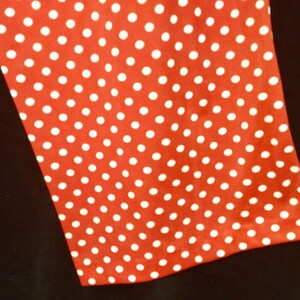 May include: Red fabric with a white polka dot pattern.