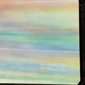 May include: A piece of iridescent glass with a layered, striped pattern in shades of pink, blue, green, and yellow.