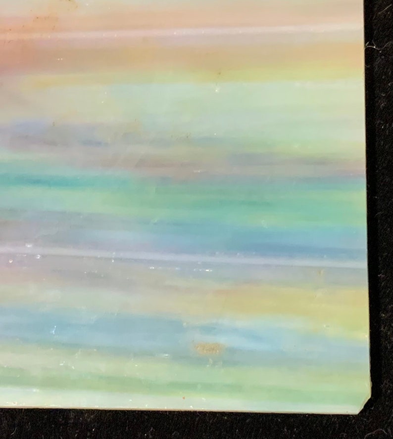 May include: A piece of iridescent glass with a layered, striped pattern in shades of pink, blue, green, and yellow.