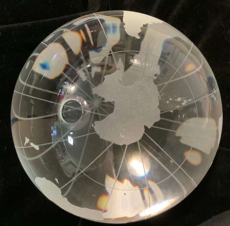 Op de afbeelding: Een heldere glazen globe met een gematteerde gegraveerde wereldkaart. De globe is een decoratief stuk met een gematteerde afwerking en een heldere glazen voet.