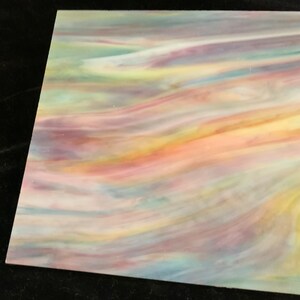 May include: A sheet of iridescent glass with a swirling pattern of pink, yellow, blue, and green colors.