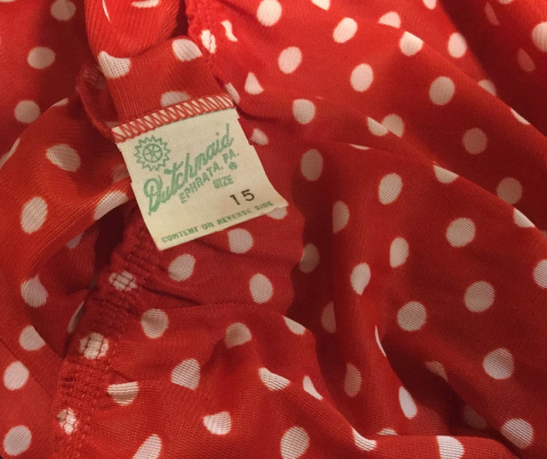 May include: Red fabric with white polka dots and a white tag that says "Dutchmaid Ephrata, PA. Size 15 Content on Reverse Side"