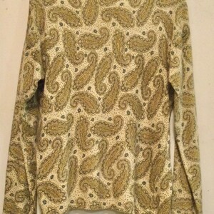 May include: A long-sleeved, cream-colored shirt with a paisley pattern in shades of gold and brown.