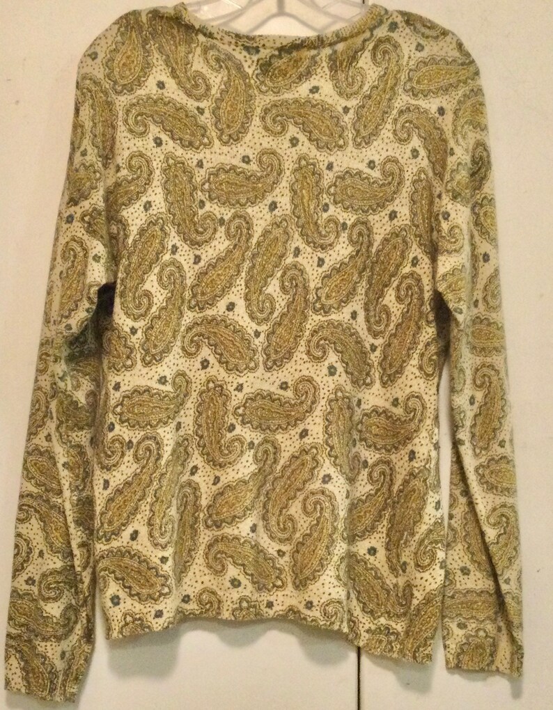 May include: A long-sleeved, cream-colored shirt with a paisley pattern in shades of gold and brown.