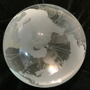 Op de afbeelding: Een matglazen globe met een witte gegraveerde wereldkaart. De globe is helder en heeft een lichte blauwe tint.