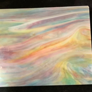 May include: A piece of iridescent glass with a swirling pattern of blue, green, yellow, orange, and pink colors.