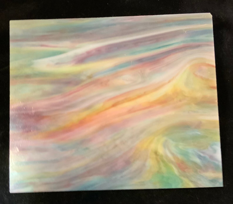 May include: A piece of iridescent glass with a swirling pattern of blue, green, yellow, orange, and pink colors.