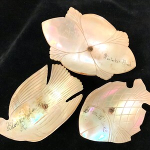 May include: Three small, decorative, iridescent, mother-of-pearl dishes shaped like a bird, a fish, and a flower. The bird dish is inscribed "Block Island, R.I.", the fish dish is inscribed "Southport, Maine", and the flower dish is inscribed "Manasquan Beach".