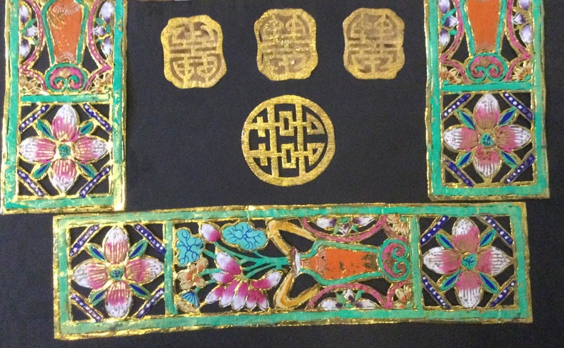 May include: A set of four gold-colored Chinese wedding decorations with intricate designs. The decorations are made of paper and are cut out in the shape of flowers, vases, and the Chinese character for "double happiness".
