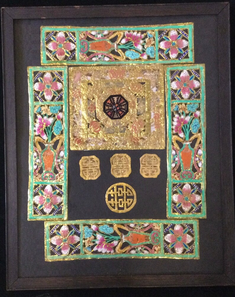 May include: A framed artwork with a black background and intricate gold and colored paper cutouts. The artwork features a central square with a smaller octagon inside, surrounded by four smaller squares. The artwork is decorated with floral motifs and the Chinese character for "double happiness" appears in the center.