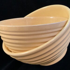 May include: Two yellow ceramic bowls, one nested inside the other. Both bowls have a ridged design.