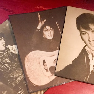 May include: Three black and white photographs of Elvis Presley. The first photo shows Elvis playing a guitar. The second photo shows Elvis in a leather jacket. The third photo shows Elvis in a black jacket with a white scarf.