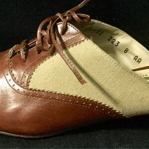 May include: Brown leather and beige canvas slip-on shoe with a lace-up detail. The shoe has a size tag that reads "223 8 AA".