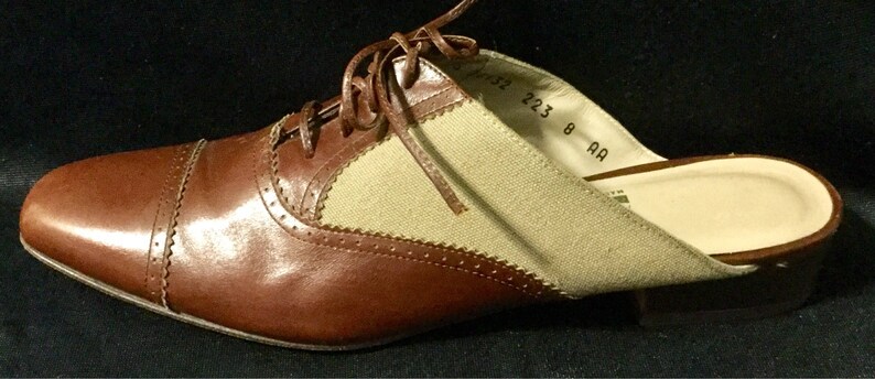 May include: Brown leather and beige canvas slip-on shoe with a lace-up detail. The shoe has a size tag that reads "223 8 AA".