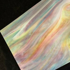 May include: A sheet of iridescent glass with a swirling pattern of pink, yellow, blue, and green colors.