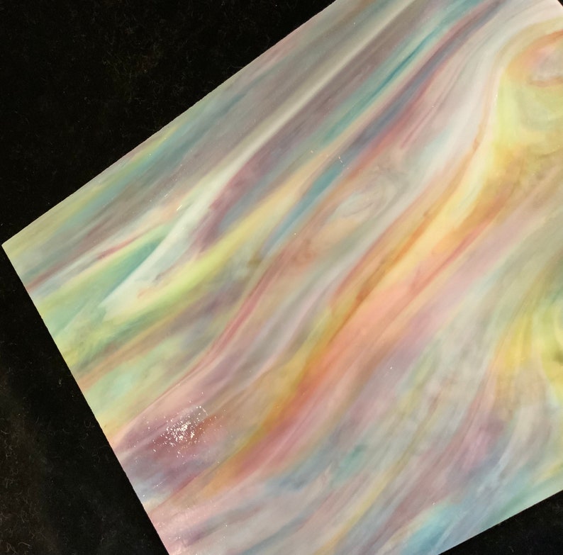 May include: A sheet of iridescent glass with a swirling pattern of pink, yellow, blue, and green colors.