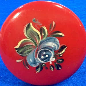 May include: A red round knob with a hand-painted blue and green floral design.