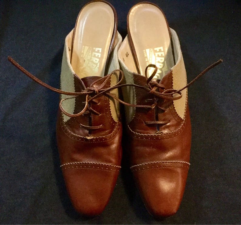 May include: A pair of brown leather shoes with beige canvas panels and laces. The shoes have a rounded toe and a low heel.