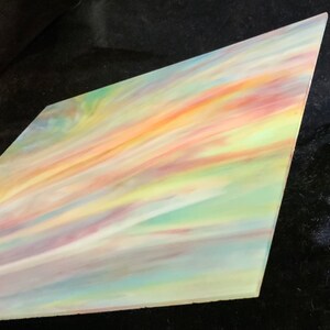 May include: A piece of iridescent glass with a swirling pattern of pastel colors, including pink, yellow, green, and blue.