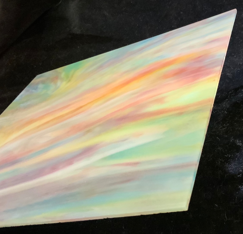 May include: A piece of iridescent glass with a swirling pattern of pastel colors, including pink, yellow, green, and blue.