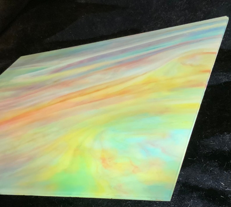 May include: A sheet of iridescent glass with a swirling pattern of yellow, orange, pink, blue, and green colors.