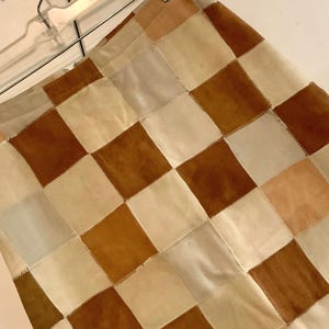 May include: A checkered skirt made of brown, beige, and light blue suede leather.