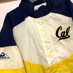 May include: A vintage jacket in navy blue, cream, and yellow. The jacket features the word "Cal" in a script font on the chest and the "APEX" logo on the sleeve. The jacket has a zip-up front and a high collar.